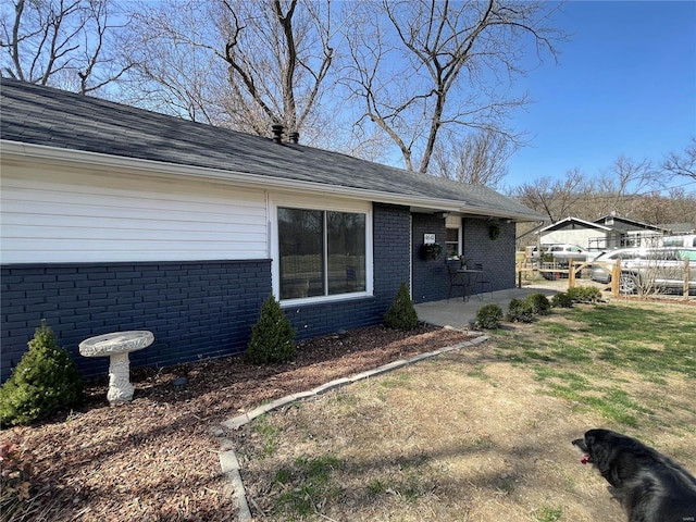 view of front facade featuring brick siding, a patio area, a front lawn, and fence