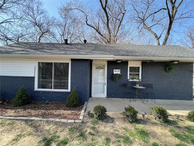 doorway to property with brick siding and a shingled roof