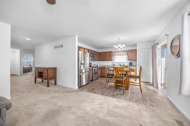 dining area featuring light carpet, visible vents, a wealth of natural light, and an inviting chandelier