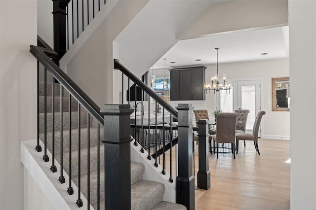 stairs with wood-type flooring and a chandelier