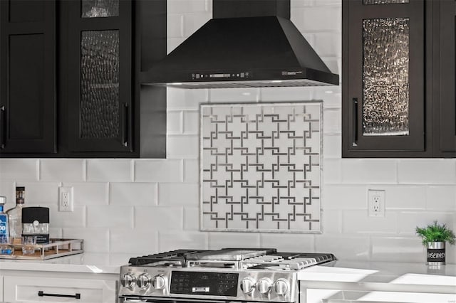 kitchen featuring tasteful backsplash, wall chimney range hood, white cabinetry, and stainless steel range with gas stovetop