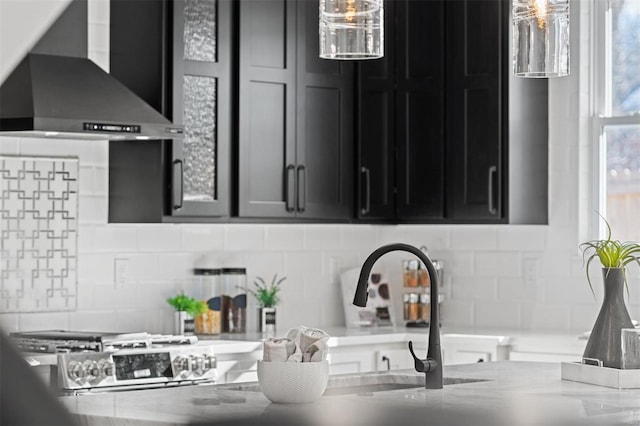 kitchen with backsplash, light stone counters, and wall chimney range hood