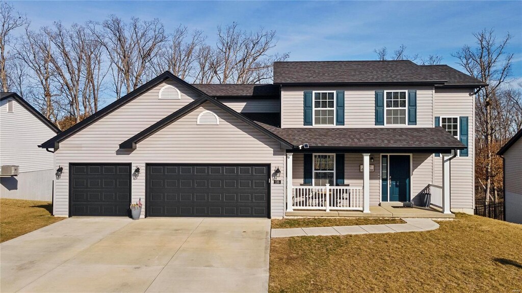 front facade with a garage, covered porch, and a front lawn