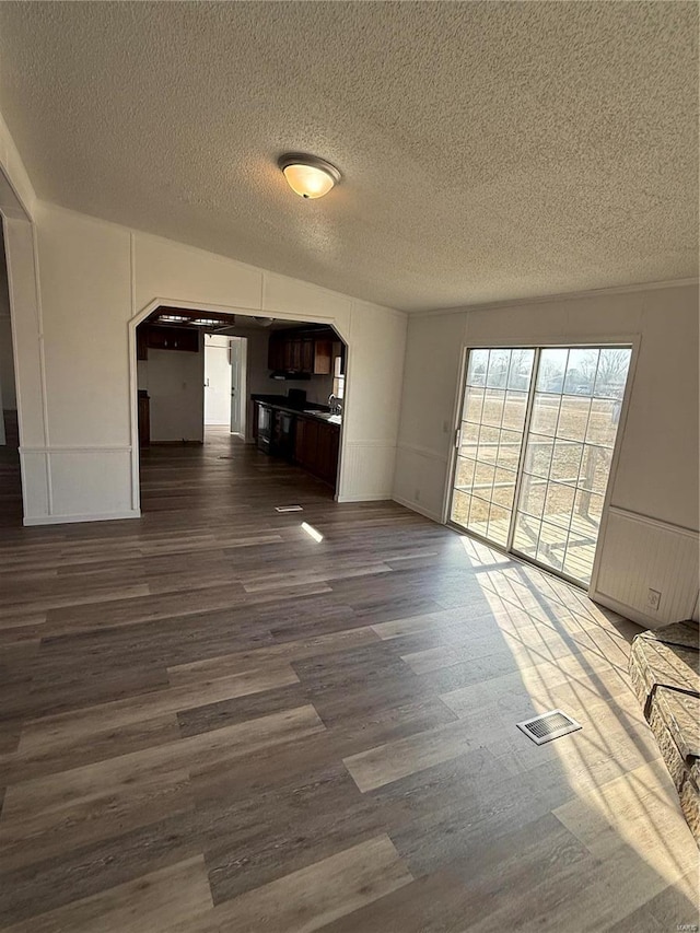 unfurnished living room featuring a textured ceiling and dark hardwood / wood-style flooring