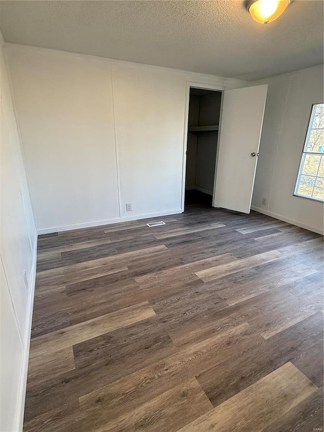 unfurnished bedroom featuring dark wood-type flooring and a textured ceiling