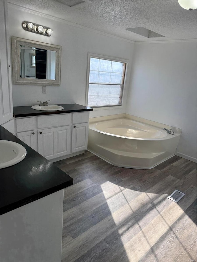 bathroom with vanity, a bath, hardwood / wood-style floors, and a textured ceiling