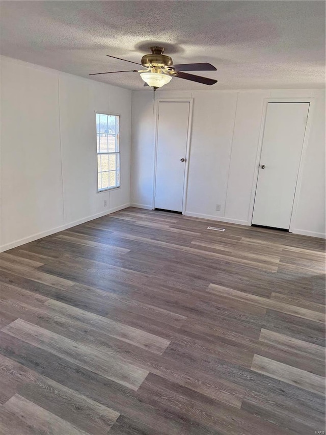 unfurnished room with ceiling fan, dark hardwood / wood-style floors, and a textured ceiling