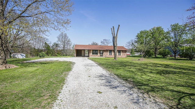 single story home featuring a front lawn and gravel driveway