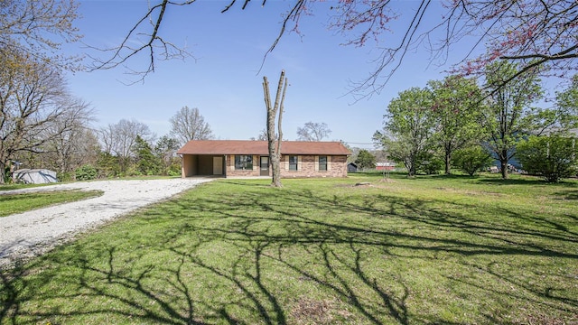 single story home featuring a front yard, gravel driveway, and an attached carport