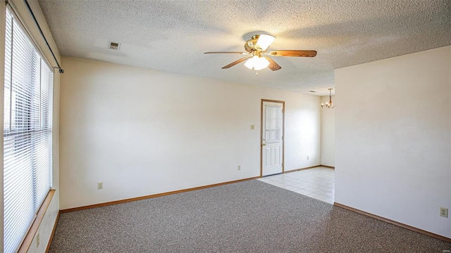 spare room with visible vents, light carpet, baseboards, a textured ceiling, and ceiling fan with notable chandelier