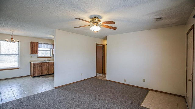 spare room featuring baseboards, a sink, a textured ceiling, and ceiling fan with notable chandelier