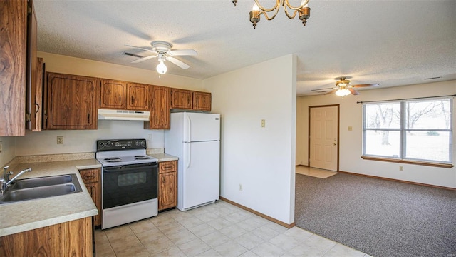 kitchen with under cabinet range hood, a sink, freestanding refrigerator, electric range oven, and ceiling fan with notable chandelier
