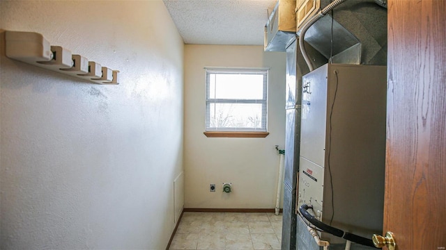 laundry area with a textured ceiling, baseboards, and heating unit