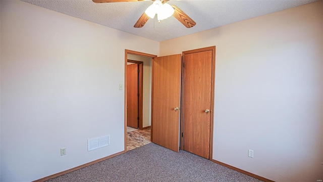 unfurnished bedroom featuring a ceiling fan, a textured ceiling, baseboards, carpet flooring, and visible vents