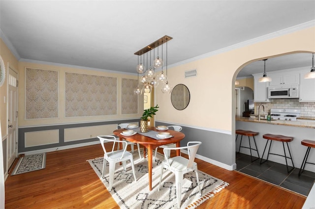 dining space featuring ornamental molding, dark hardwood / wood-style floors, and sink