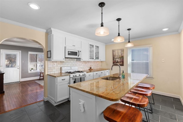 kitchen with sink, white cabinetry, white appliances, light stone countertops, and a kitchen island with sink