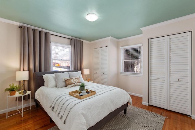 bedroom featuring multiple closets, wood-type flooring, and crown molding