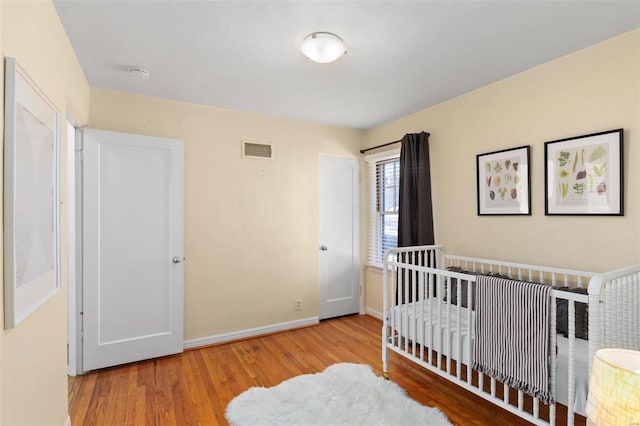 bedroom featuring light hardwood / wood-style floors and a nursery area