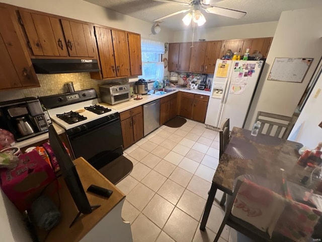 kitchen with light tile patterned floors, stainless steel dishwasher, gas range, white fridge with ice dispenser, and under cabinet range hood