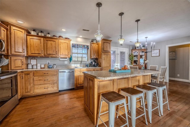 kitchen featuring hanging light fixtures, stainless steel appliances, hardwood / wood-style floors, and a kitchen island