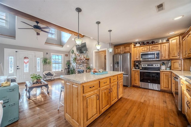 kitchen with a center island, vaulted ceiling, light hardwood / wood-style flooring, appliances with stainless steel finishes, and pendant lighting