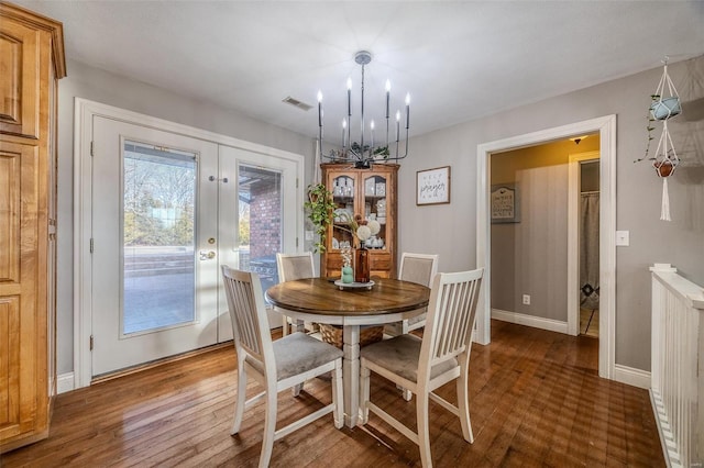 dining area with dark wood-type flooring, a chandelier, and french doors