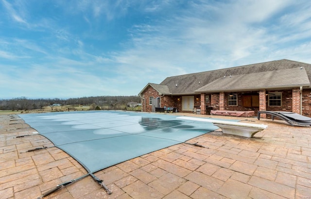 view of swimming pool featuring a patio and a diving board