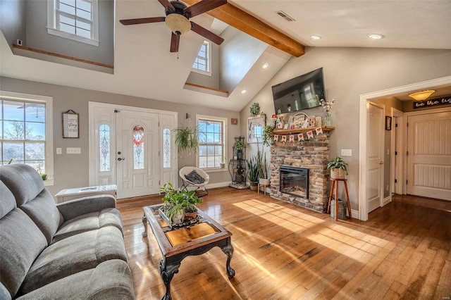 living room with beamed ceiling, wood-type flooring, a fireplace, and high vaulted ceiling