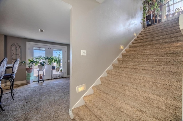 stairway featuring french doors and carpet