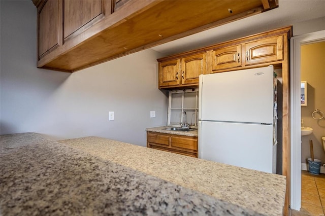 kitchen featuring sink, light tile patterned floors, and white fridge