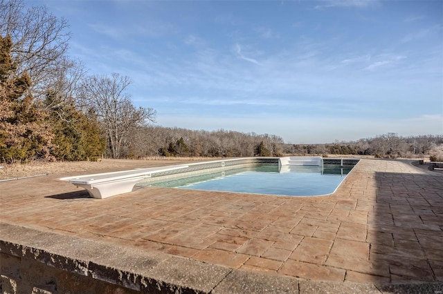 view of pool with a patio area and a diving board