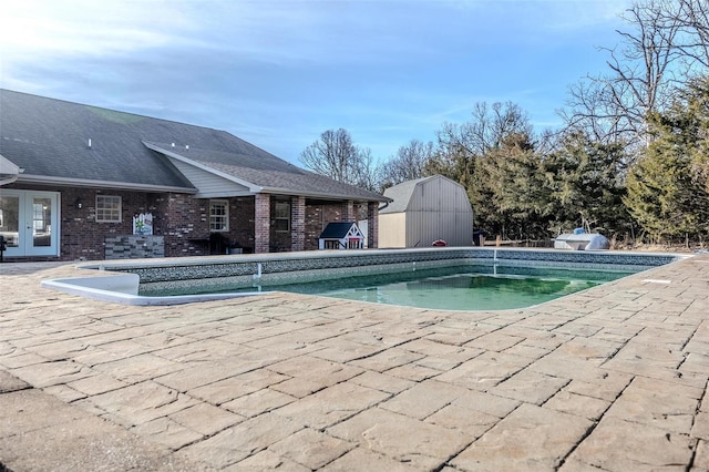 view of pool with a patio and a storage shed