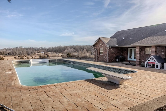 view of swimming pool with a patio area and a diving board