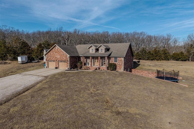 view of front of property featuring a garage, a front yard, a trampoline, and covered porch