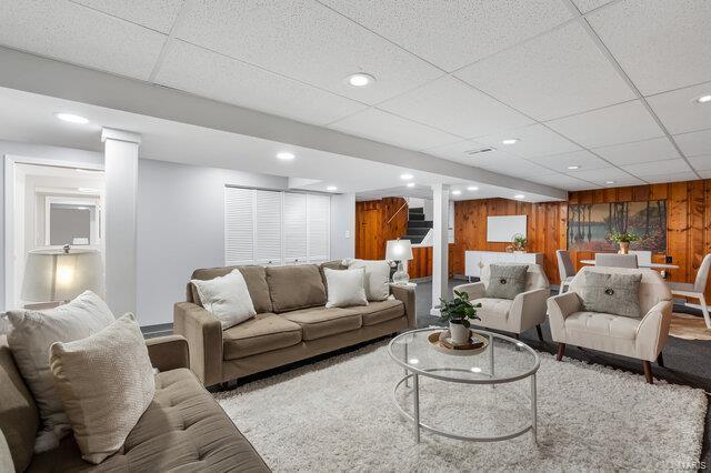 living room with wooden walls and a paneled ceiling