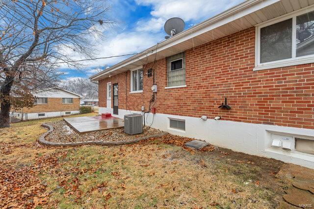 view of side of property with cooling unit, a yard, and a patio area