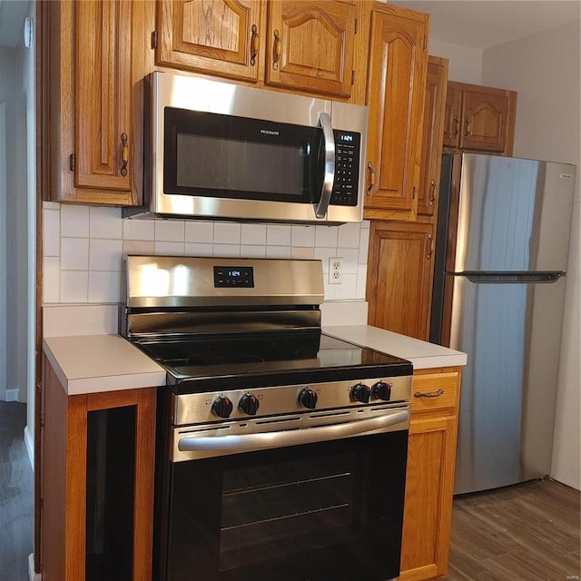 kitchen with stainless steel appliances, dark hardwood / wood-style flooring, and decorative backsplash