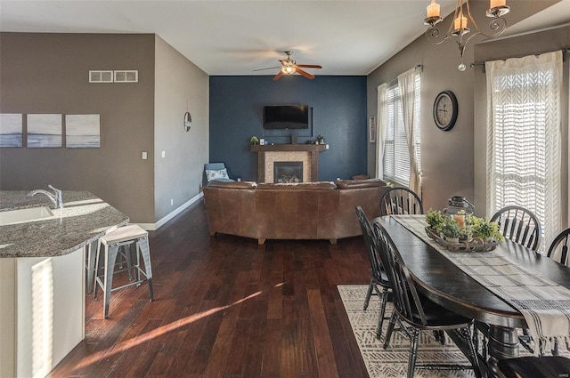 dining room with sink, ceiling fan with notable chandelier, and dark wood-type flooring