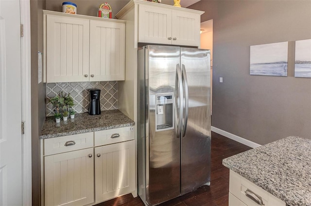 kitchen with tasteful backsplash, stainless steel fridge, light stone counters, and white cabinets