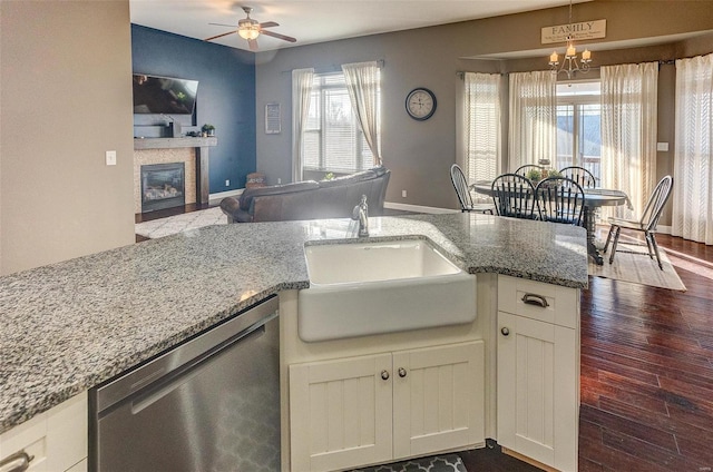 kitchen featuring white cabinetry, sink, stainless steel dishwasher, and light stone counters