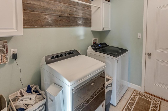 washroom with cabinets, washing machine and clothes dryer, and light tile patterned flooring