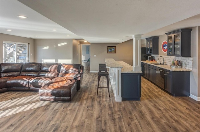 living room featuring dark hardwood / wood-style flooring, wet bar, and decorative columns