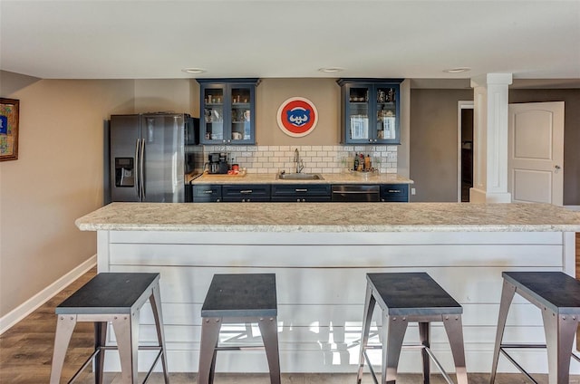 kitchen featuring sink, appliances with stainless steel finishes, light stone countertops, hardwood / wood-style floors, and decorative backsplash