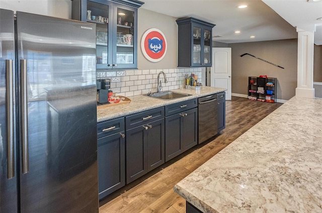 kitchen featuring appliances with stainless steel finishes, dark hardwood / wood-style flooring, sink, and ornate columns