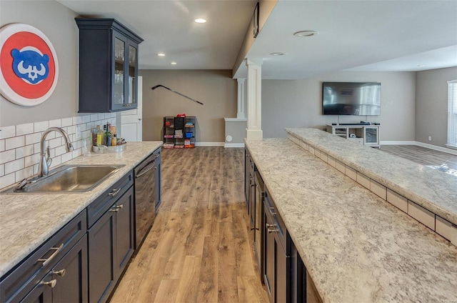 kitchen featuring ornate columns, black dishwasher, sink, decorative backsplash, and light hardwood / wood-style flooring