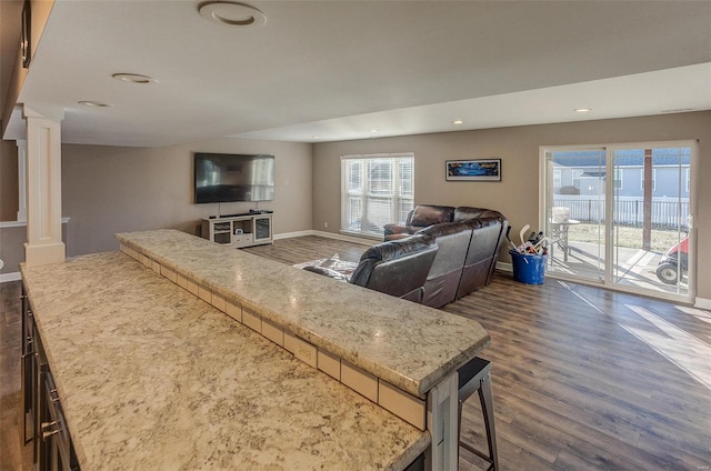 living room featuring dark wood-type flooring and decorative columns