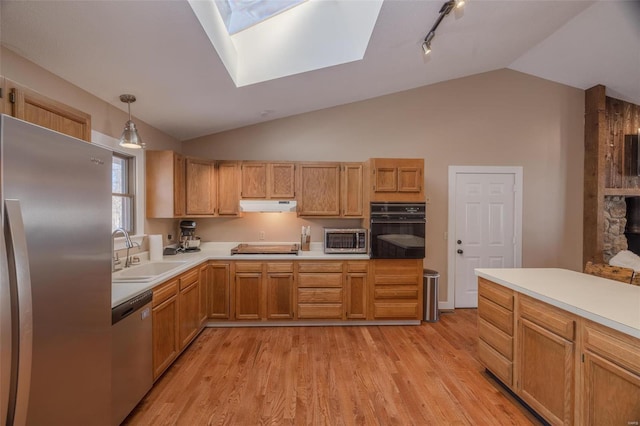 kitchen with lofted ceiling with skylight, sink, hanging light fixtures, stainless steel appliances, and light wood-type flooring