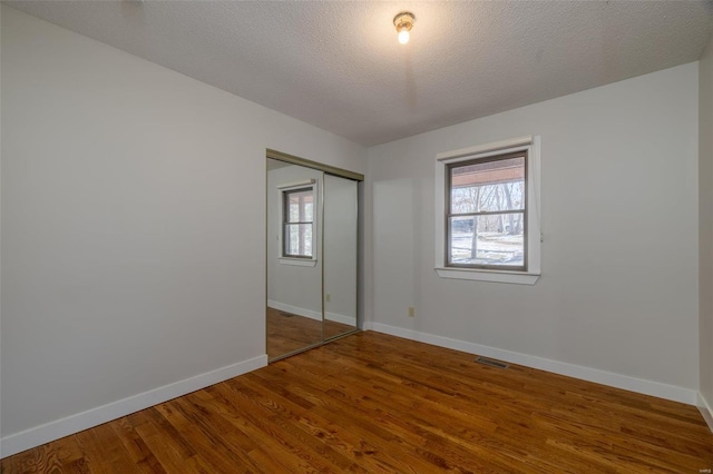 unfurnished bedroom featuring hardwood / wood-style flooring, a textured ceiling, and a closet