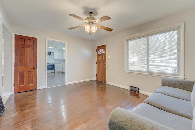 living area with ceiling fan, baseboards, and wood finished floors