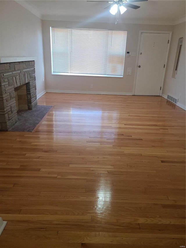 unfurnished living room with hardwood / wood-style flooring, ceiling fan, crown molding, and a fireplace